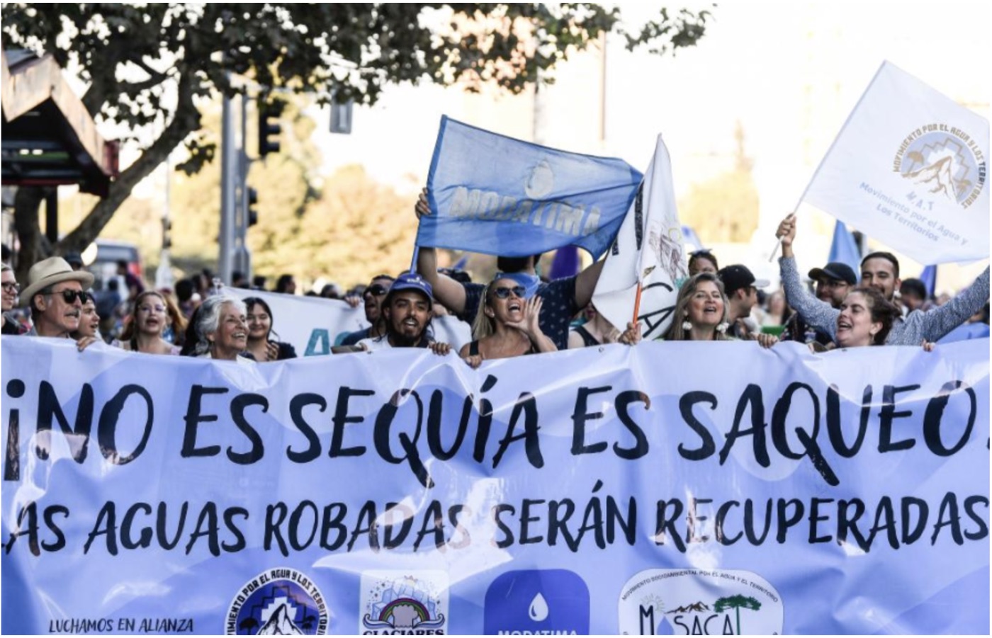Protesters in Chile holding a banner reading No es sequía, es saqueo