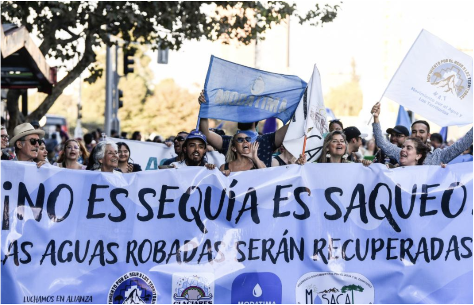 Protesters in Chile holding a banner reading No es sequía, es saqueo